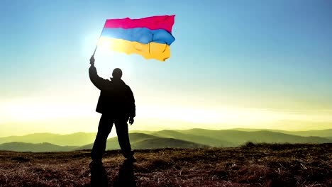 hombre ganador de silueta exitosa agitando la bandera armenia en la cima del pico de la montaña. fondo de bucle de cinemagraph