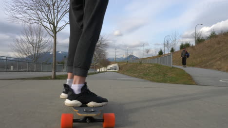 foto de seguimiento de una persona en una rueda de longboard montando en una carretera asfaltada
