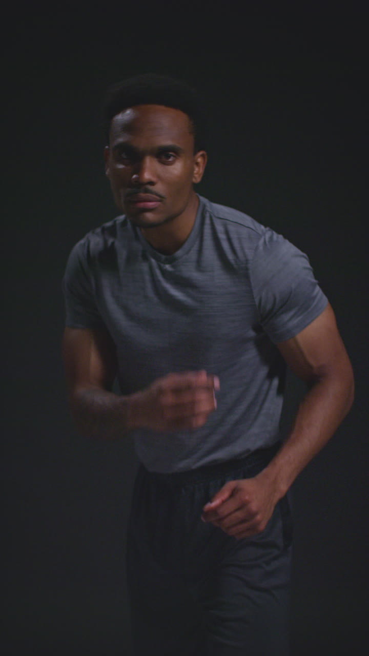 Vertical Video Studio Portrait Of Male Boxer Training In Gym Sparring Towards Camera And Warming Up Preparing For Fight Against Black Background