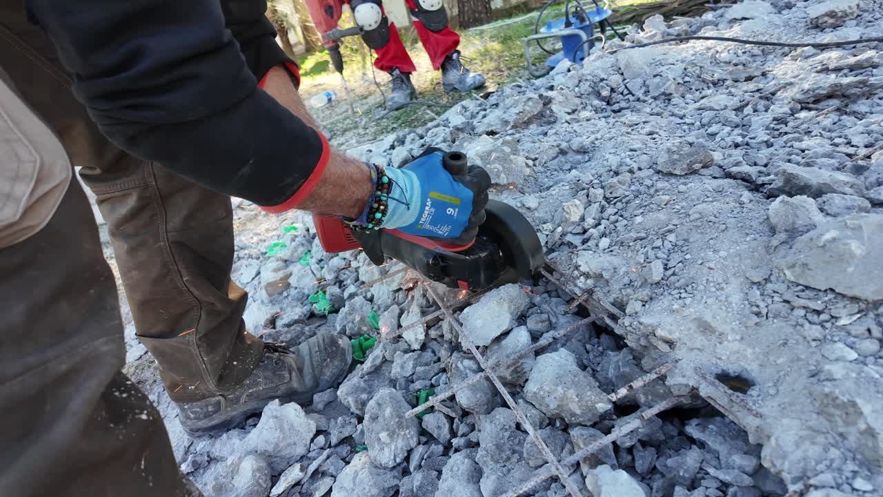 Close up view of man cutting steel fiber-reinforced concrete's construction iron with a round iron cutting machine,sparks over debris.