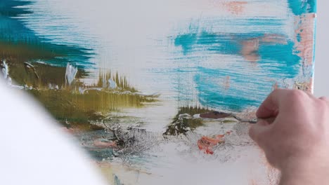the artist paints an abstract picture he is focused on work painting on an easel in his art studio - the artist paints an abstract picture, he is focused on work, painting on an easel in his art studio, creative atmosphere