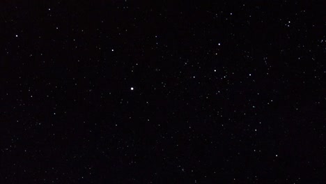 panning shot across multiple shining bright stars on dark black sky.