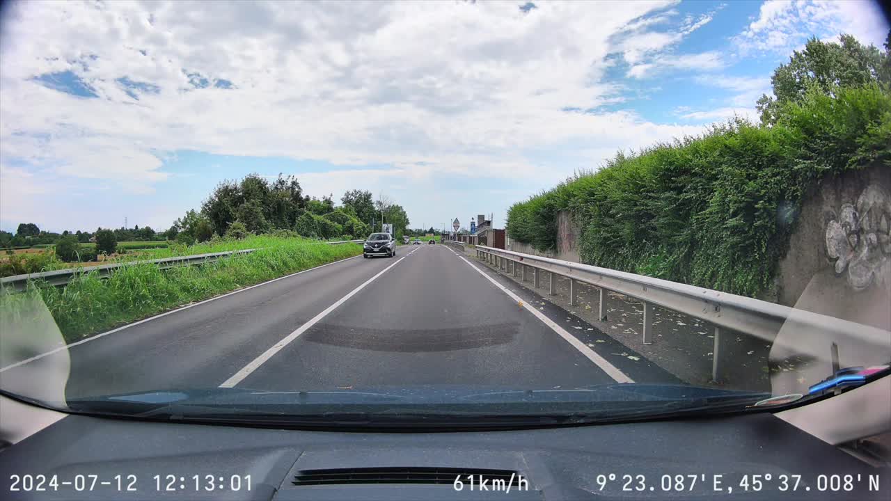 Dash cam footage of daytime drive on road in Italy through roundabout with traffic