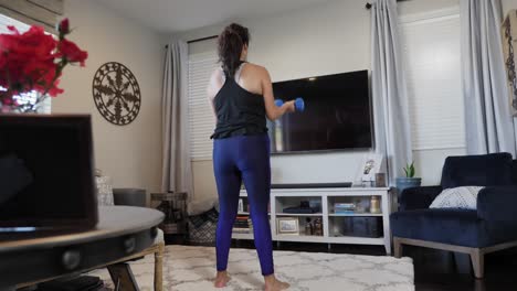hispanic female working out with weights in living room, sliding shot capturing fitness during the day