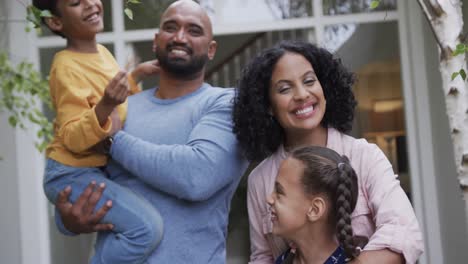 Portrait-of-happy-biracial-parents-with-son-and-daughter-in-garden