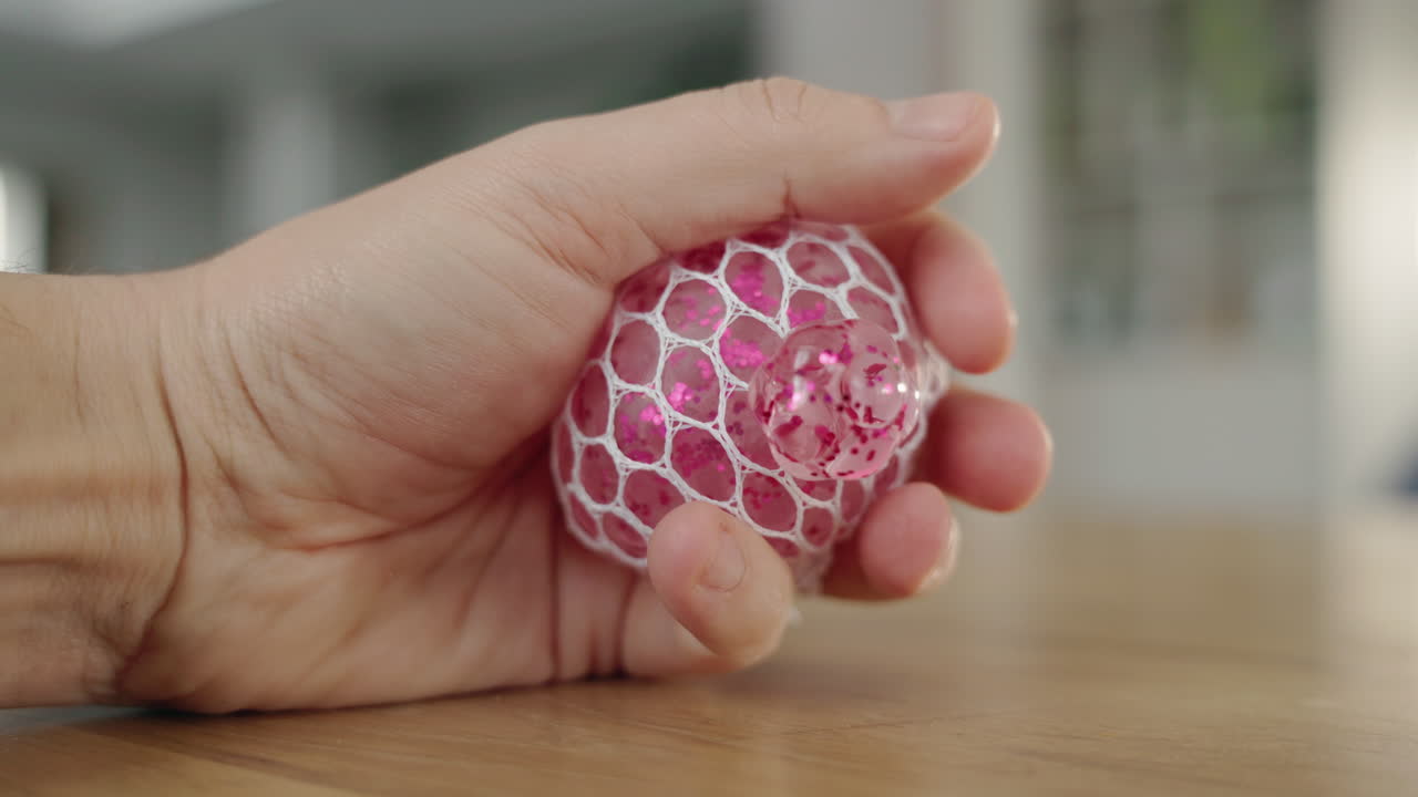 persona que sostiene una pelota de estrés de brillo rosa