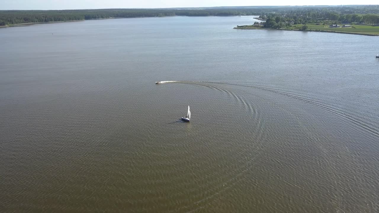 toma aérea inclinada hacia abajo de un velero y una moto de agua navegando en un lago de lublin, polonia