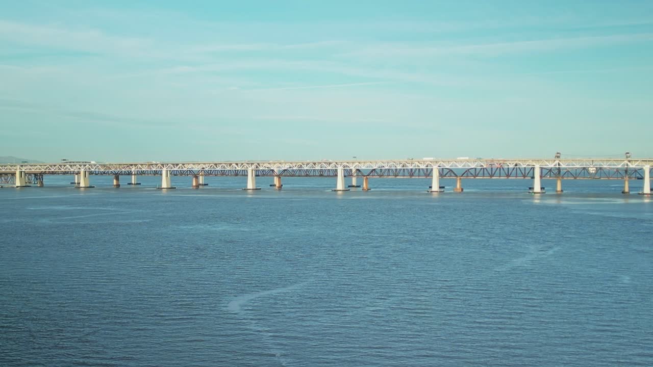 Aerial establishing static of Carquinez Strait bridges in Martinez, California, with calm waters and gentle ripples under soft sky