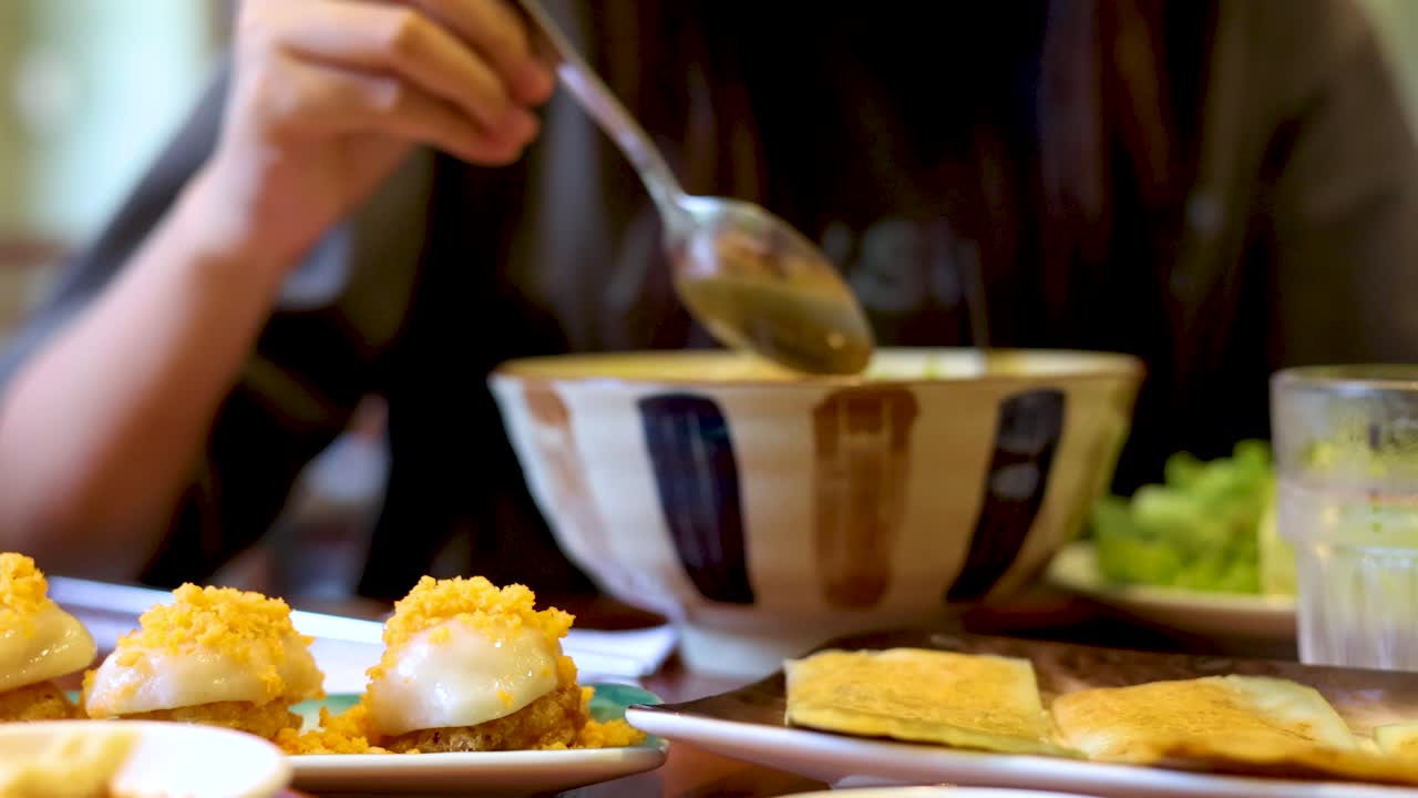 Close-up shot of a woman using a phone before eating noodles from a ceramic bowl