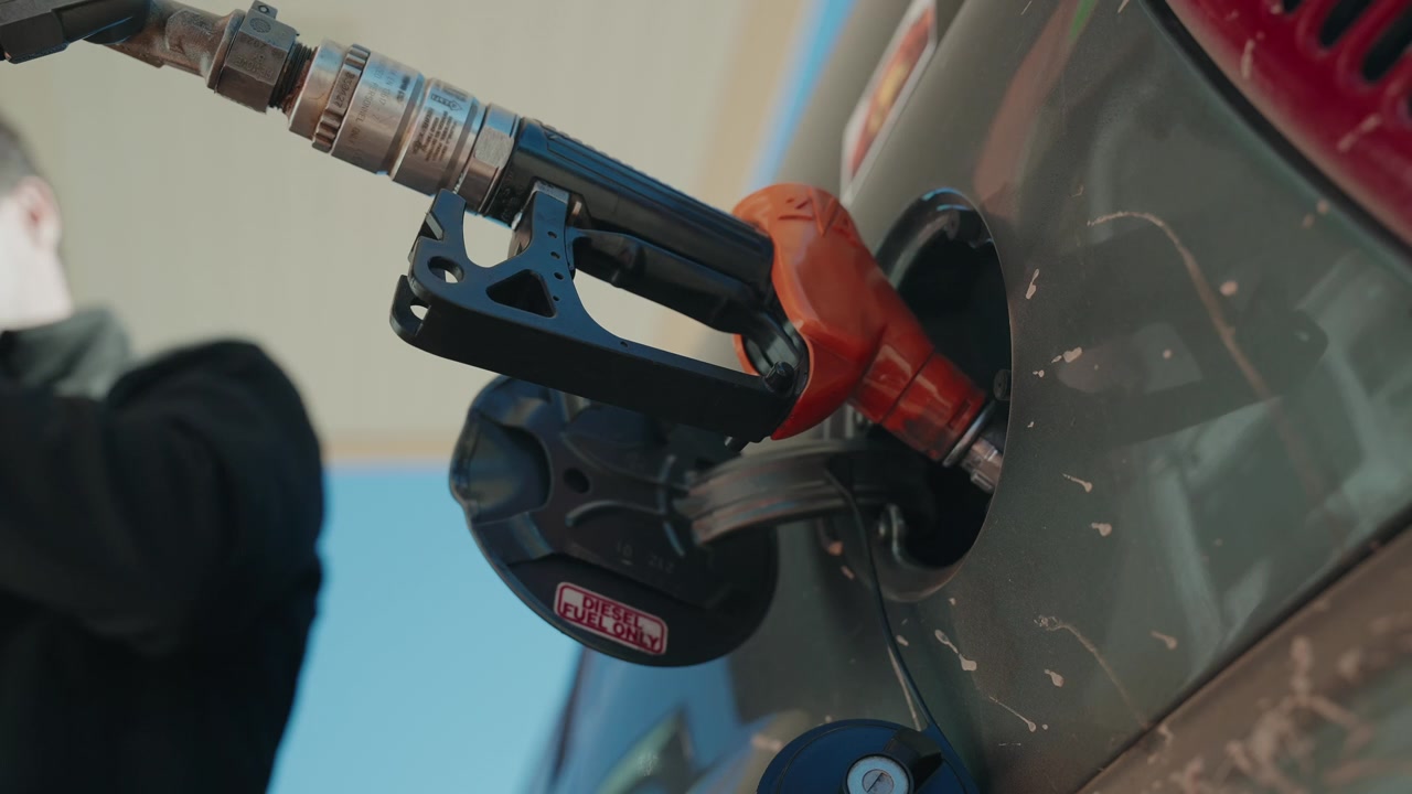Pistola del diesel inserita nel bocchettone del serbatoio di un'auto durante il rifornimento in una stazione di servizio.