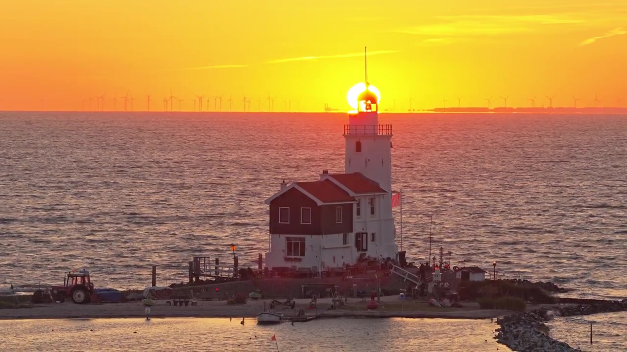 Bellissimo tramonto sul faro storico Paard van Marken. Il sole scende sotto l'orizzonte, proiettando un caldo bagliore arancione sul mare e sul paesaggio