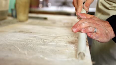 Mid-section-of-potter-removing-clay-dust-from-pipe