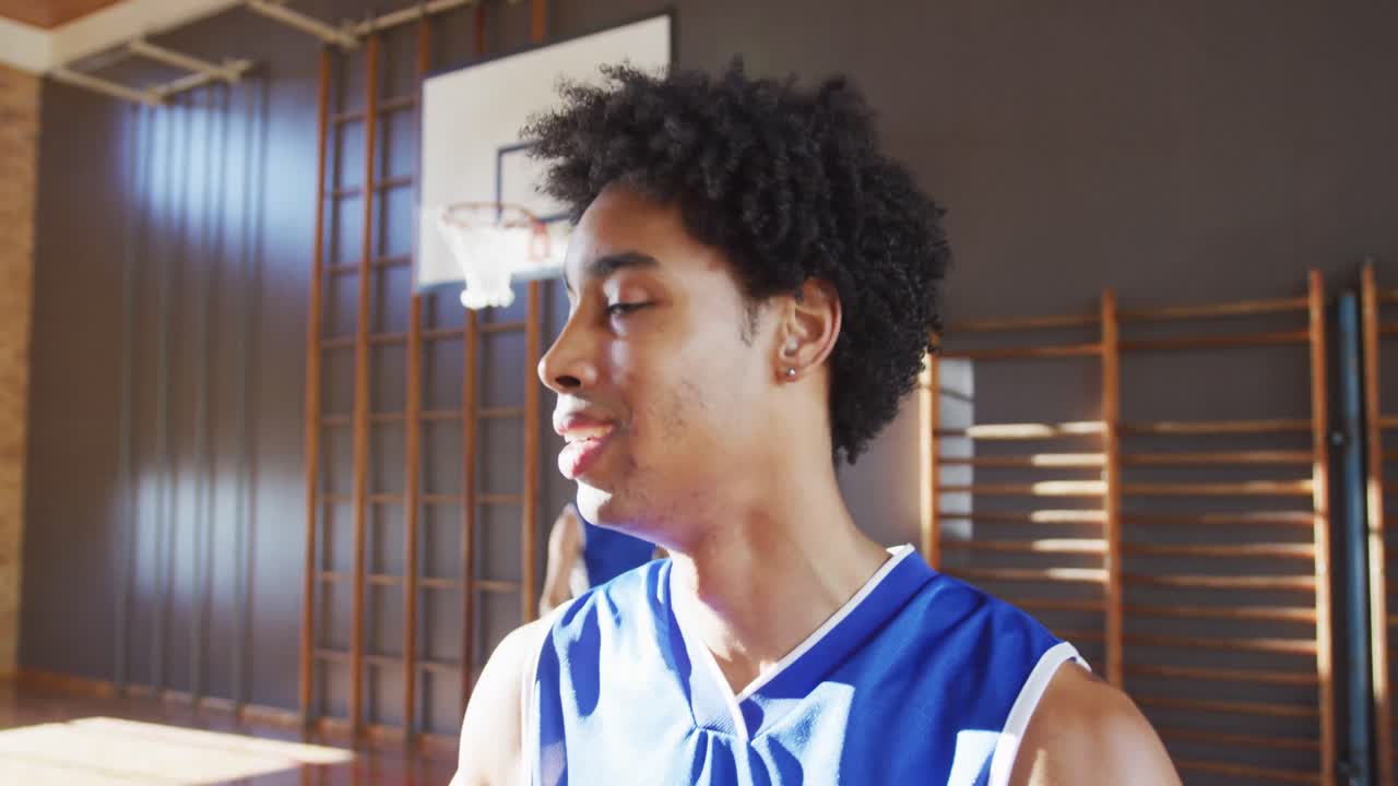 Portrait of african american male basketball player with team in background