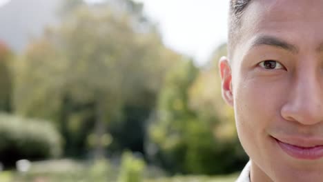 portrait of happy biracial man smiling in sunny garden, copy space, slow motion