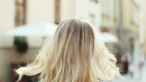 rear view of caucasian young blonde woman walking down the street