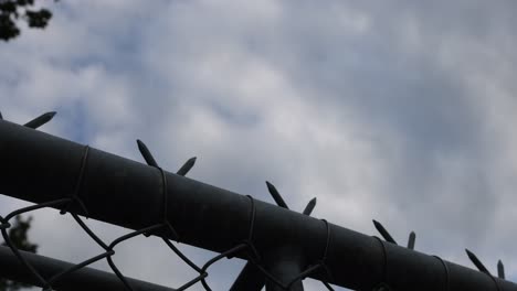 Close-up-of-barbed-wire-of-industrial-factory-against-cloudy-sky---bottom-up-slide-shot