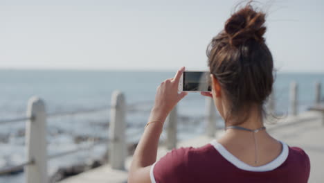 retrato de una hermosa mujer joven turista tomando fotos usando un teléfono móvil disfrutando de las vacaciones de verano haciendo turismo en la playa costera tecnología de cámara móvil