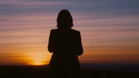 Woman&#039;s Silhouette Against a Vibrant Sunset Sky