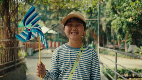 smiling girl with windmill in a park