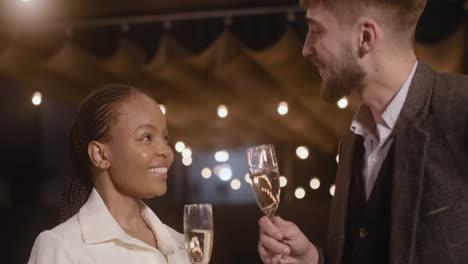 man and woman talking to each other and toasting at new year's eve party