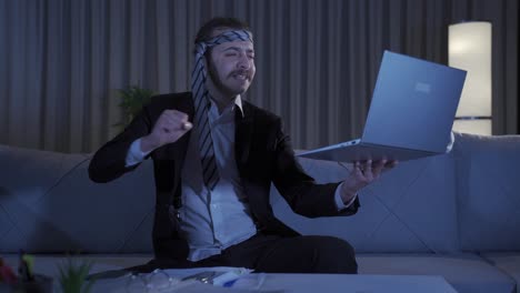 hombre de negocios gracioso trabajando en una computadora portátil en casa después de una fiesta nocturna.