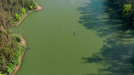 aerial view dolly in of the curauma lagoon, with rowing teams practicing and passing each other, chile