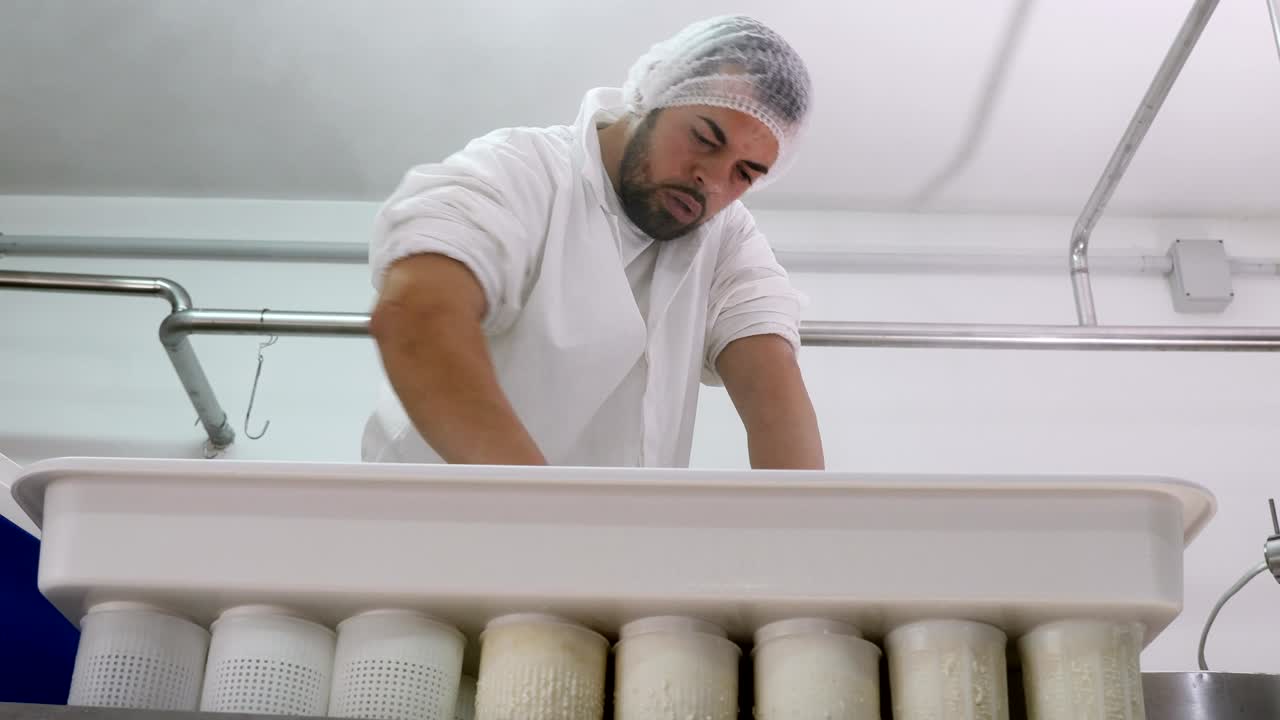 worker in diary cheese factory working on ricotta cheese