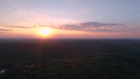 high altitude flight during sunrise over a forest in france. aerial drone shot