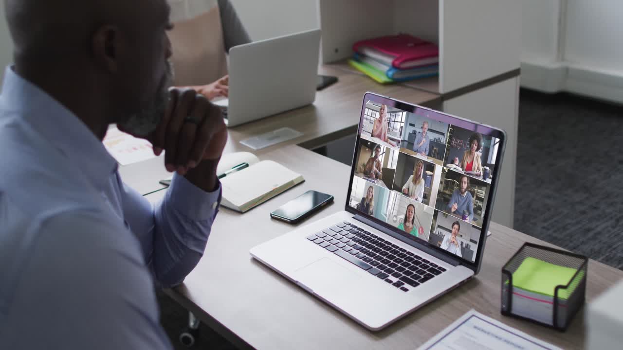 African american senior man having a video conference on laptop with office colleagues at office