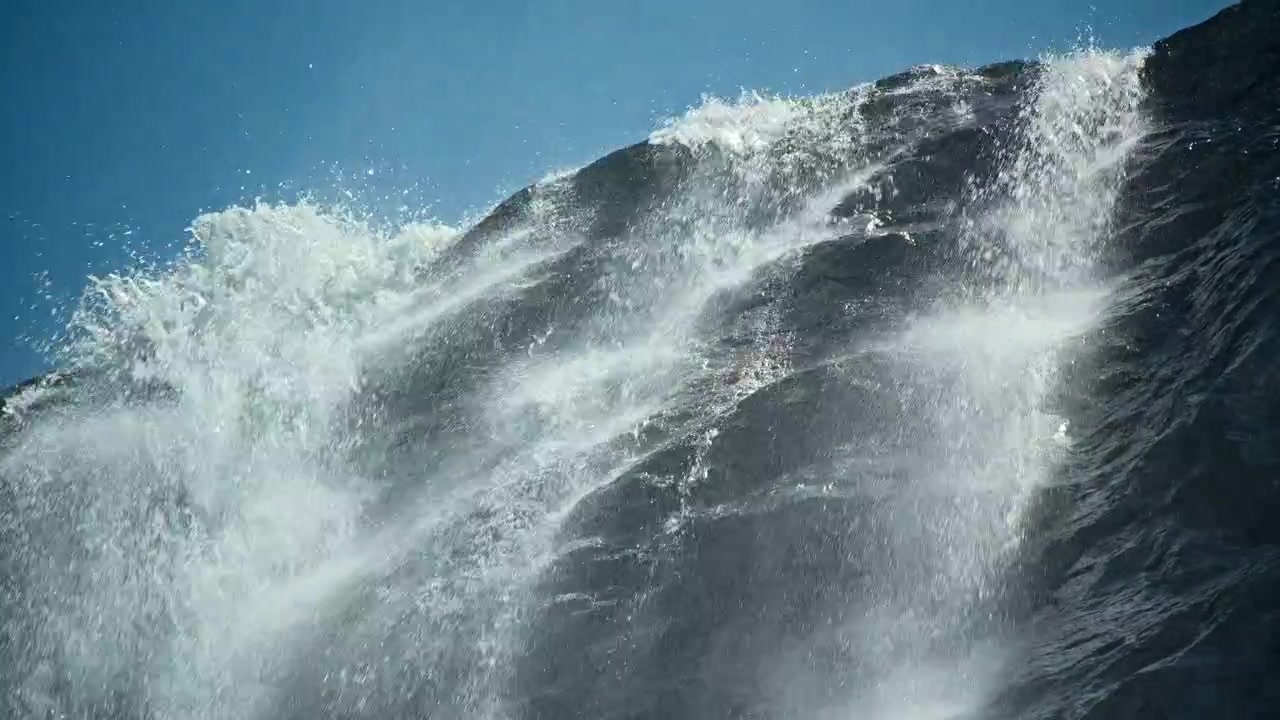 Powerful Waterfall Cascading Down a Rocky Cliff Under a Clear Blue Sky