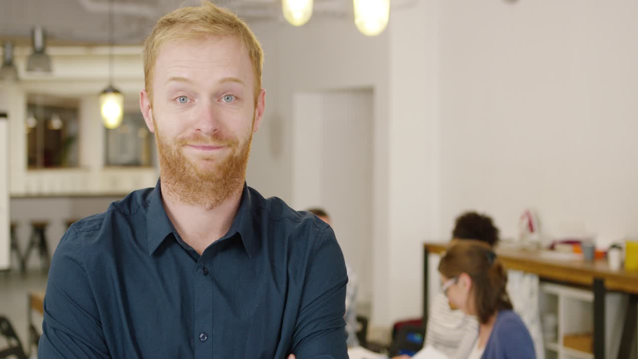 hombre posando en la oficina con compañeros de trabajo