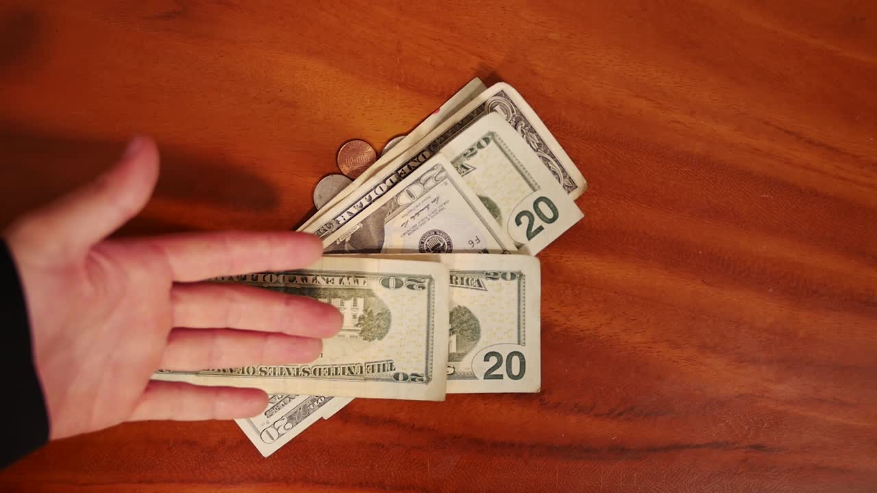 Overhead close up shot of man hand showing dollar bills and cents on wood table