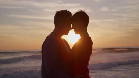 pareja tocando las frentes junto al mar durante el atardecer