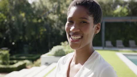 portrait of happy african american woman looking at camera and smiling in garden, slow motion