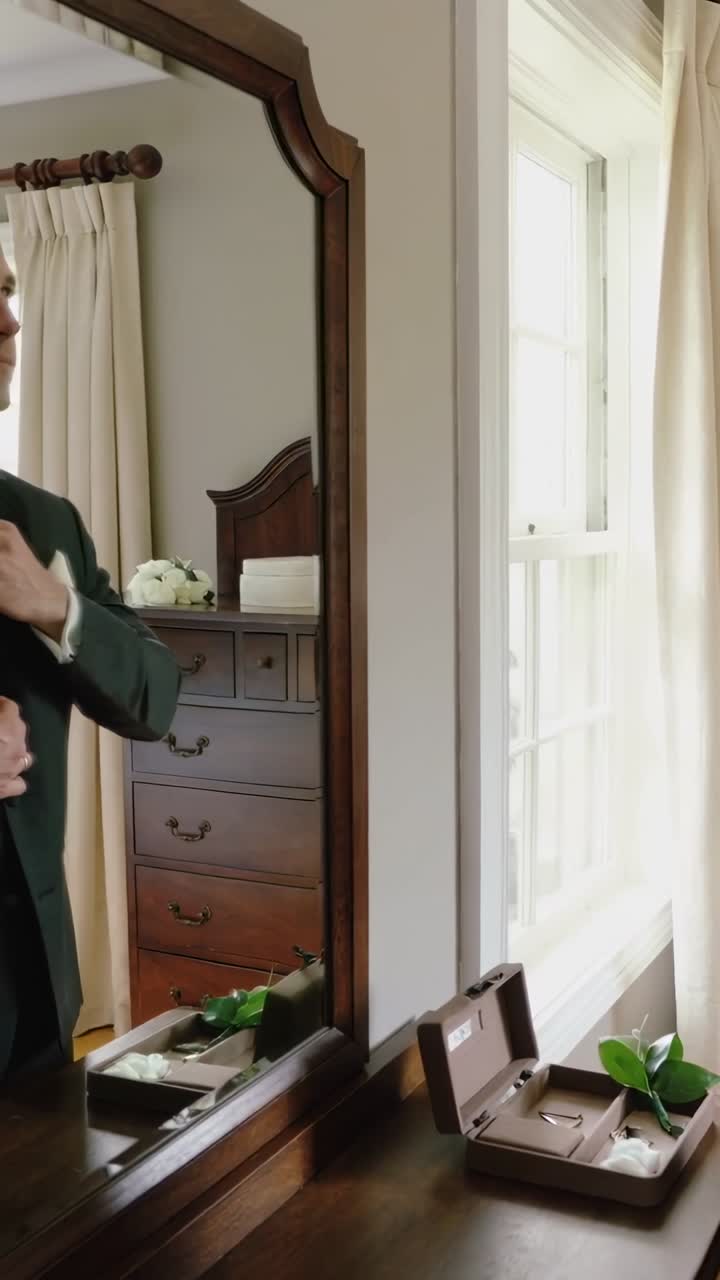 Vertical video: Getting ready, man in suit adjusting cuffs and tie at dresser with box, copy space