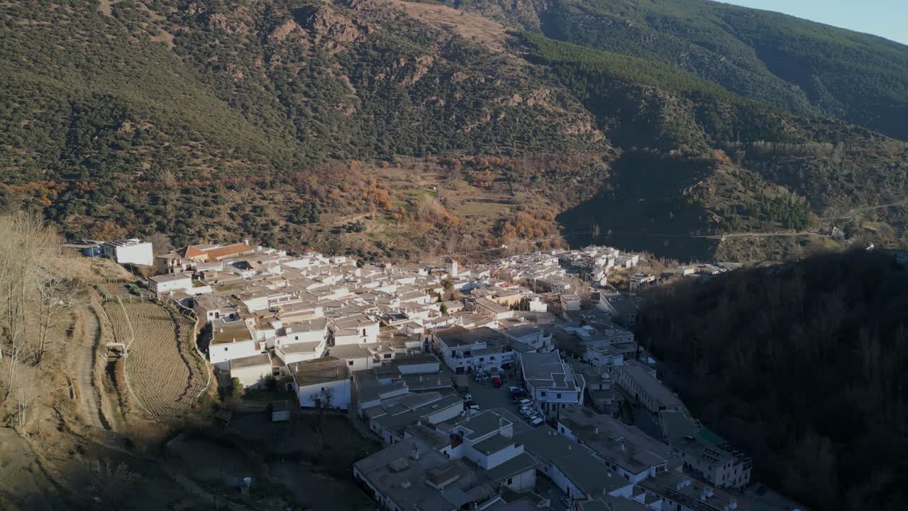 Vista aerea di un tradizionale villaggio bianco incastonato in una valle di montagna.