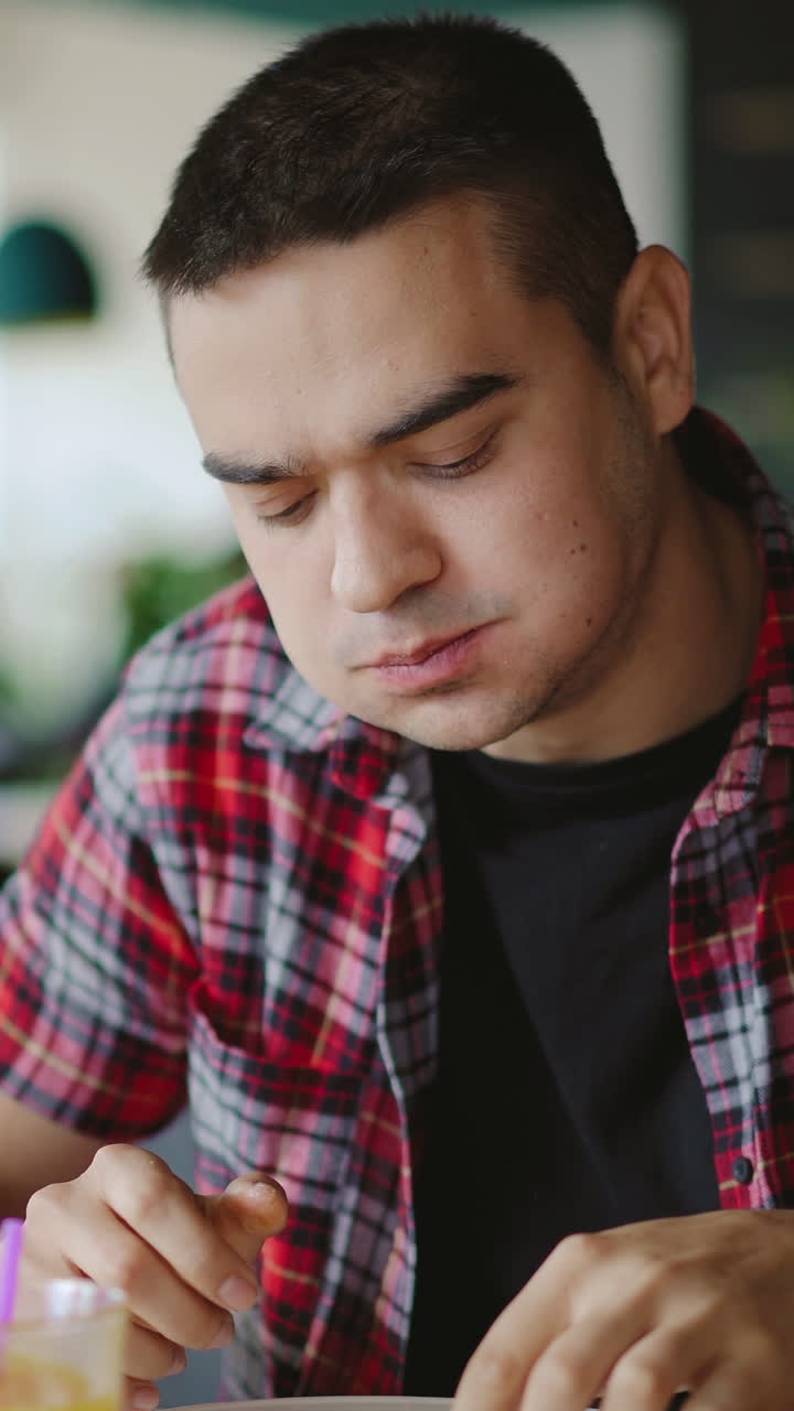 a young man is eating pizza and drinking juice in the cafe at lunch. Vertical video