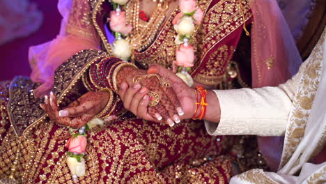 newly married indian traditional couple romantically holding hands. lavish wedding dress and bride jewellery in frame
