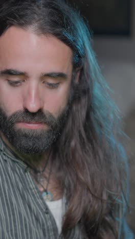 man with long hair and beard drinking tea while holding a guitar