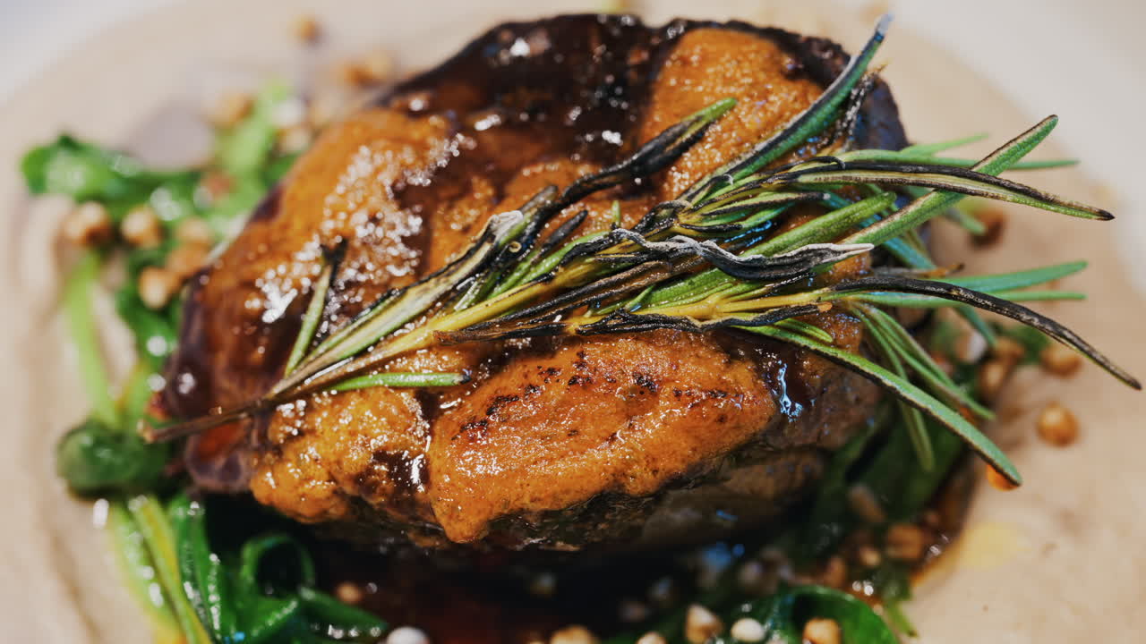 Close up of a beautifully plated beef filet, topped with a golden crust and garnished with rosemary