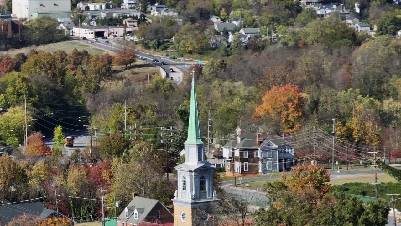 Aerial orbit shot of church tower in american town during sunset time in autumn. Colorful trees in american neighborhood. Lynchburg, Virginia