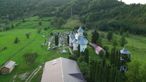 flying towards medieval church with a graveyard in palanca town, bacau county, western moldavia, romania