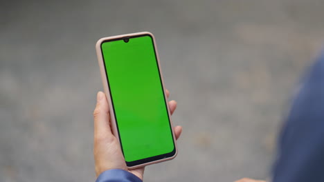 finger tapping green smartphone closeup. woman hand scrolling chroma key device