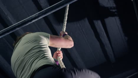 man climbing a rope in the gym practicing strength in slow motion