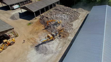 aerial top-down shot jcb excavator unloading crushed stone inside sand and rock mining quarry