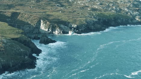 slow aerial zoom out of cable car travelling over waves crashing into shore line reveliving irish rocky island