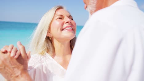 una pareja feliz y jubilada bailando juntos en una playa tropical.