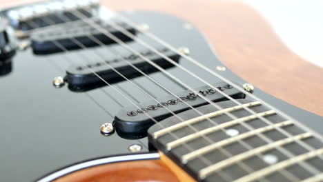 wood grain electric guitar strings being plucked with a pick