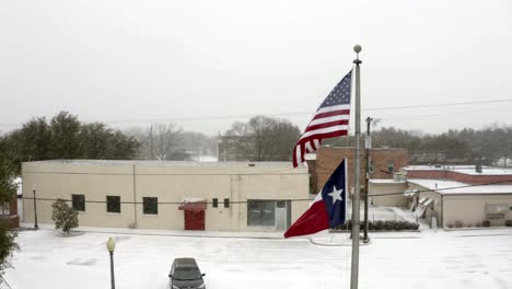 disparo giratorio de la bandera de los ee.uu. y la bandera de texas soplando en el viento junto con las ráfagas de nieve