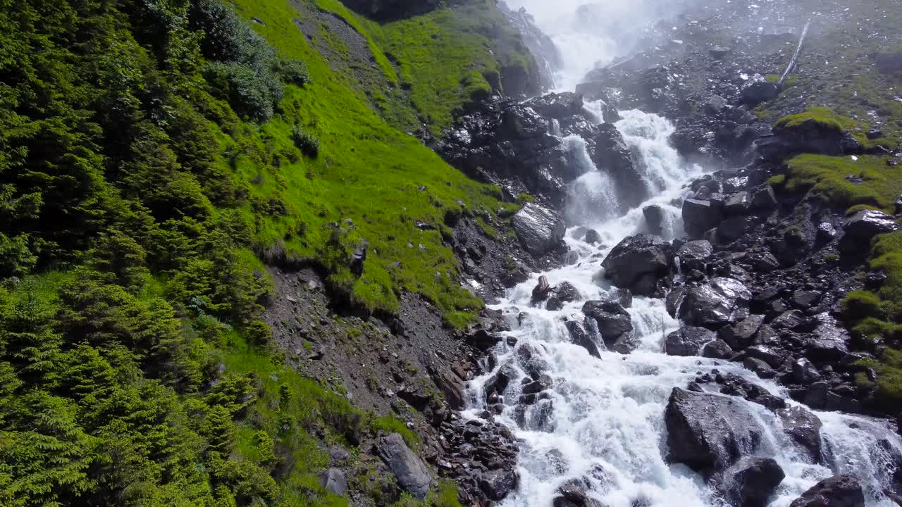 dolly empuja hacia el agua blanca en cascada entre las rocas negras en el desfiladero del valle verde